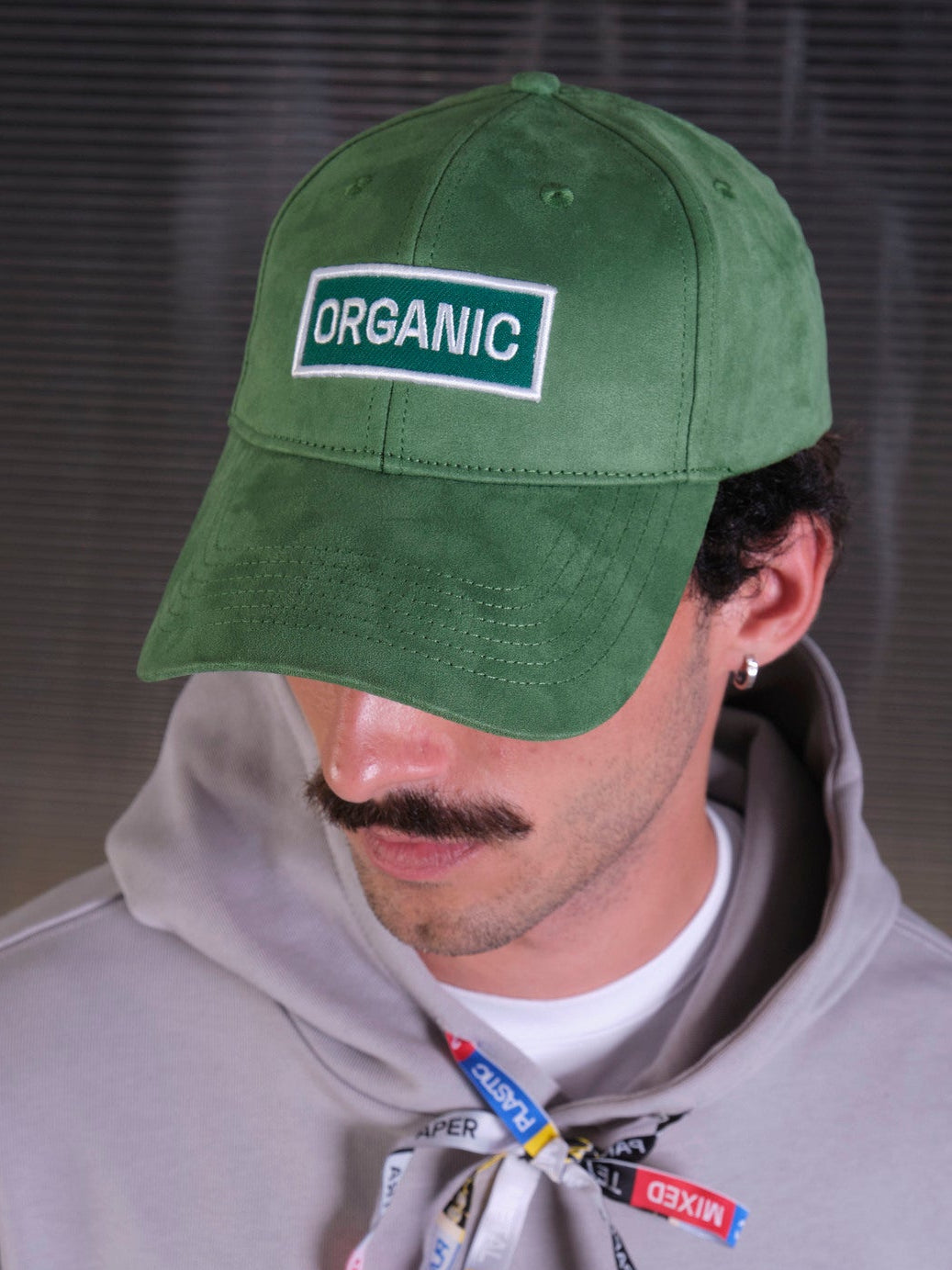 bABP Organic green eco-suede hat from the Signature Collection, close-up portrait view of a model with a mustache wearing a gray hoodie, highlighting the white "ORGANIC" logo patch