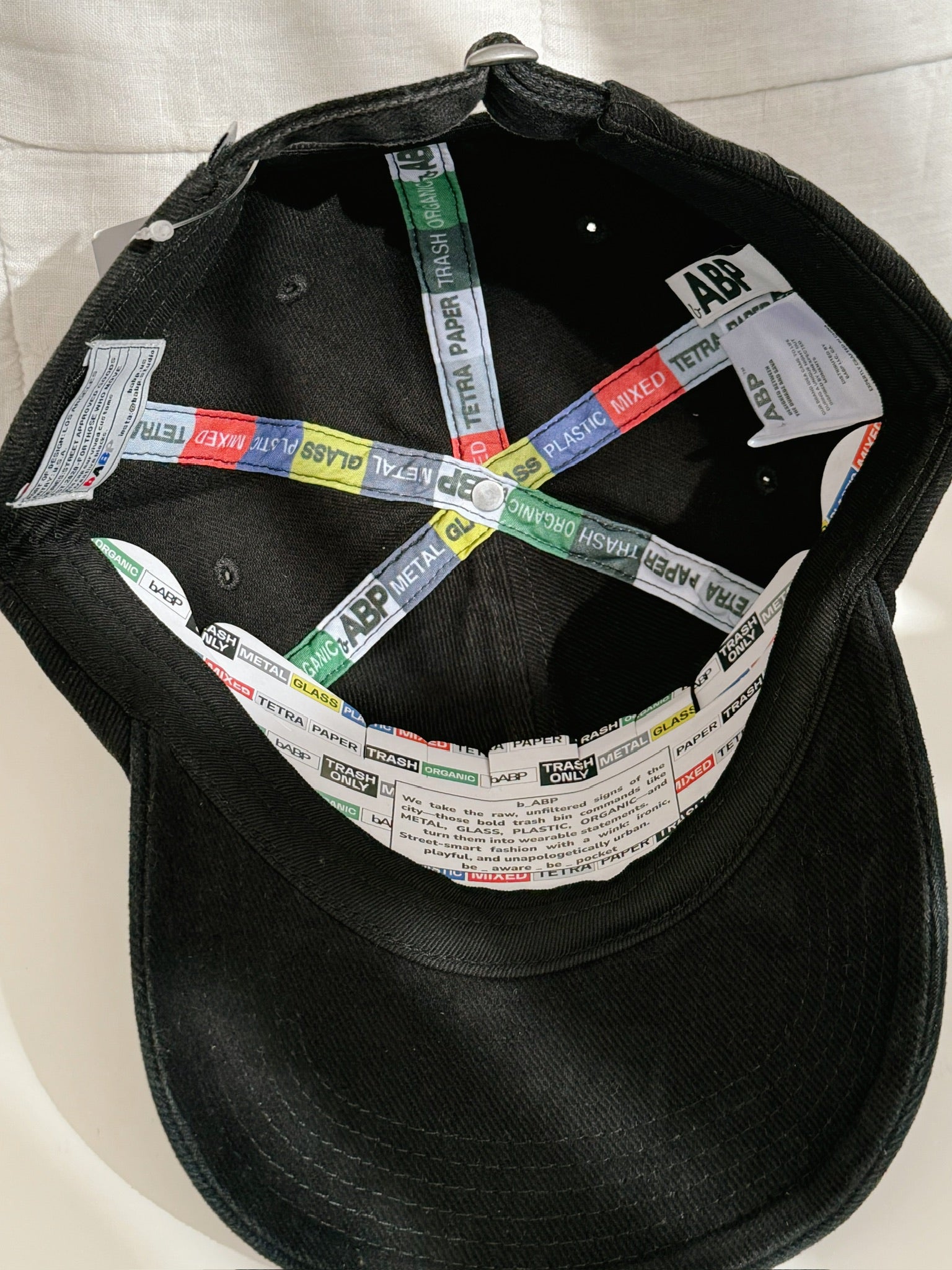 Interior view of bABP "COMPOST" black washed cotton hat from the B-SIDE collection, showing branded interior taping, logo patches with hidden details, signature tags, and custom branded cardboard insert